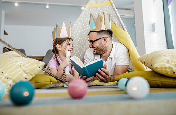Kindern vorlesen: Ein Vater liest seiner Tochter eine Märchen-Geschichte vor.