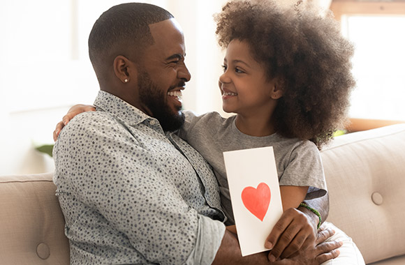 Daughter gives her dad a homemade Father's Day card. Daughter gives her dad a homemade Father's Day card.