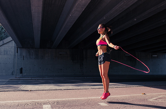 Rope skipping – woman skipping using a pink rubber skipping rope.