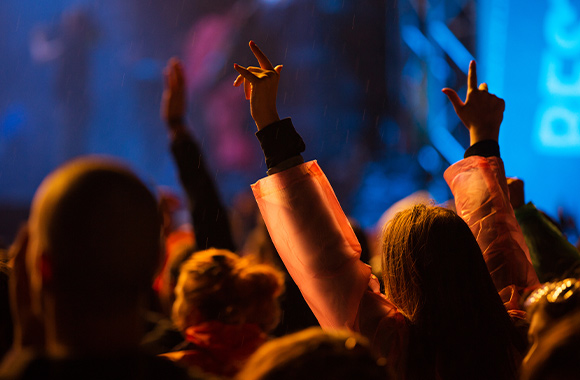 A festival in the rain: festivalgoers wearing rain ponchos are sticking their arms up in the air. A festival in the rain: festivalgoers wearing rain ponchos are sticking their arms up in the air.