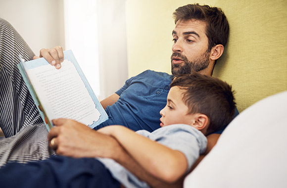 Vader leest zijn zoontje uit een kinderboek voor.