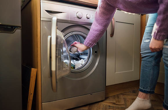 Detersivo lavatrice ecologico: una donna aggiunge del detersivo bio al bucato. Detersivo lavatrice ecologico: una donna aggiunge del detersivo bio al bucato.
