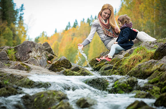 Moeder en dochter zitten bij een beekje in het bos en luisteren naar het ruisende water. Moeder en dochter zitten bij een beekje in het bos en luisteren naar het ruisende water.