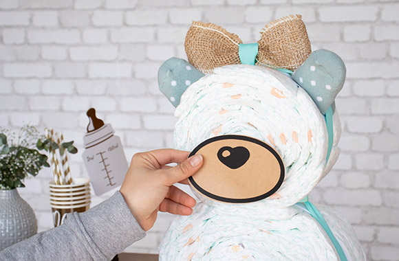 Ourson en couches: créer un visage pour le petit ours avec du papier cartonné et une tétine. Ourson en couches: créer un visage pour le petit ours avec du papier cartonné et une tétine.