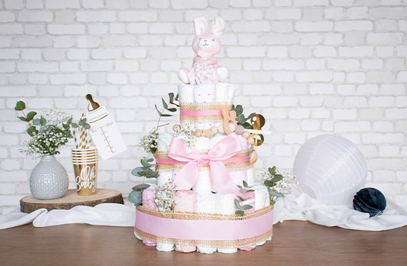 Gâteau de couches décoré pour une fille et rempli de diverses surprises pour bébé.
