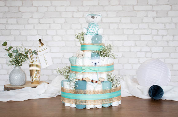 Gâteau de couches décoré avec des couleurs neutres et accompagné de différents cadeaux pour bébé.