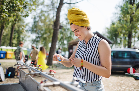 Festival hygiene: a young woman brushing her teeth at a sink at a festival.