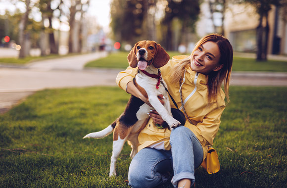 Consejos para tener un perro: una joven con su perro en un parque urbano.