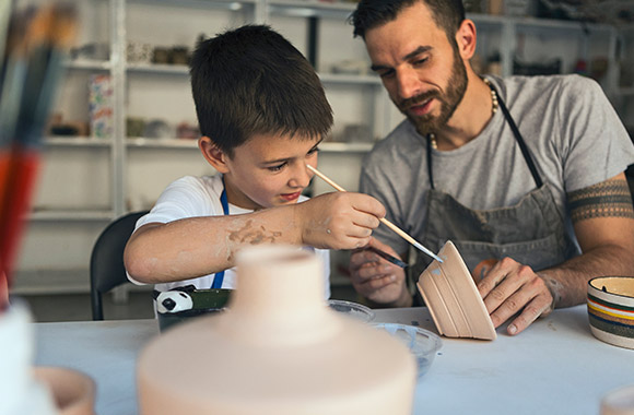 Sorties en famille : un père et son fils participent à un cours de poterie.