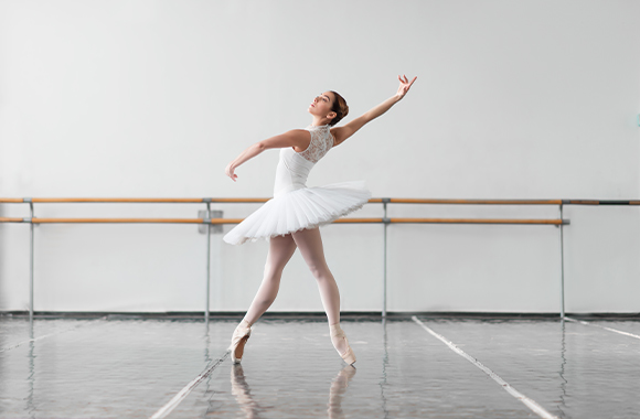 Baletní oblečení: baletka s tutu sukní pózuje na špičkách.