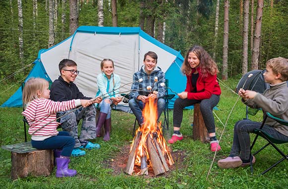 Ferienlager – Kinder grillen Marshmallows über einem Lagerfeuer.