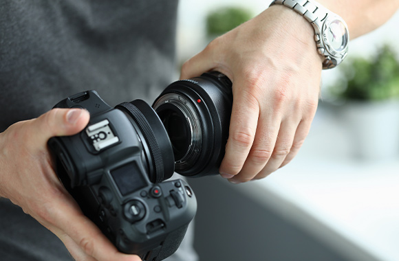 Lenses for beginners – a man is changing the lens on his camera. Lenses for beginners – a man is changing the lens on his camera.