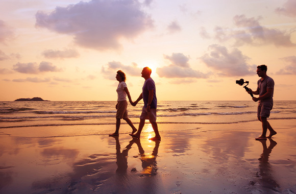 Videography – a hobby filmmaker filming a couple at the beach. Videography – a hobby filmmaker filming a couple at the beach.