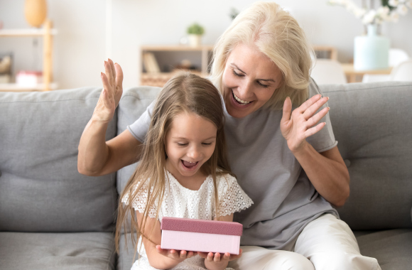 Gifts for children aged 2 and over. A granddaughter opens a present from her grandmother.