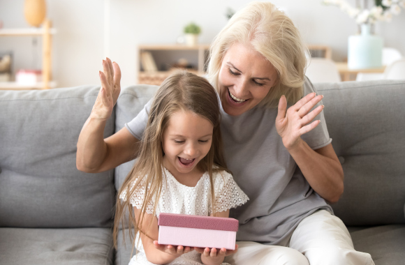 Gifts for children aged 2 and over. A granddaughter opens a present from her grandmother. Gifts for children aged 2 and over. A granddaughter opens a present from her grandmother.