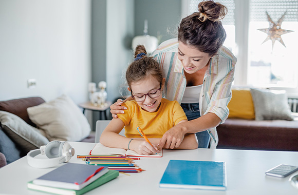 Úkoly pro děti – maminka dcerce pomáhá s domácími úkoly.