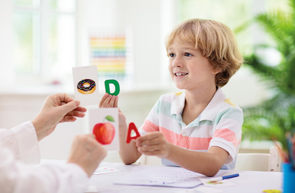 Tecniche di apprendimento per bambini: bambino assegna le lettere al cibo corrispondente.