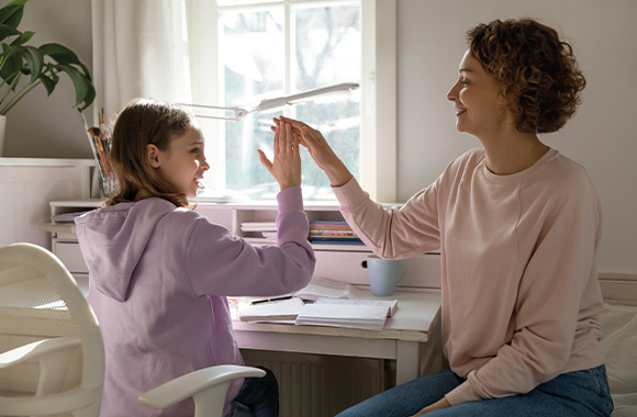 Goede leersfeer: moeder en dochter geven elkaar een high-five als het huiswerk af is.