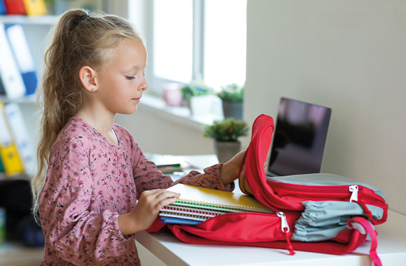 Organizzare il materiale scolastico: bambina prepara lo zaino scolastico. Organizzare il materiale scolastico: bambina prepara lo zaino scolastico.