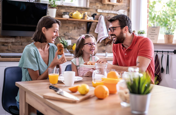 Preparar la vuelta al cole después de vacaciones: una familia desayuna en casa.