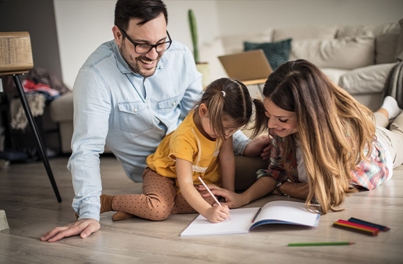 Het vergemakkelijken van de start van school - kind tekent met stiften samen met ouders. Het vergemakkelijken van de start van school - kind tekent met stiften samen met ouders.
