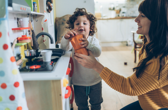 Gift for 3-year-olds: a little boy plays with his mother in a play kitchen.