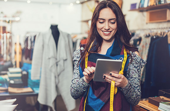 A fashion management professional working on a tablet in a clothes shop.