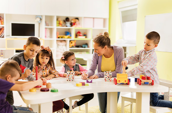 Peuterschool - groep schilderen en spelen aan tafel.