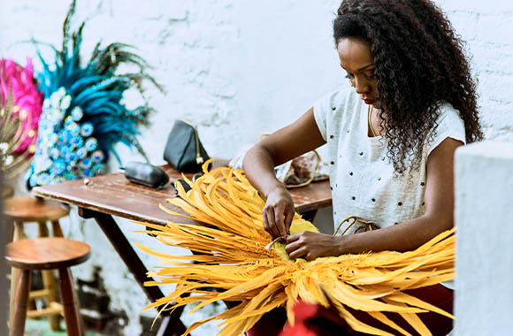 Creative jobs in the fashion industry: a costume designer working on a colourful piece of headwear. Creative jobs in the fashion industry: a costume designer working on a colourful piece of headwear.