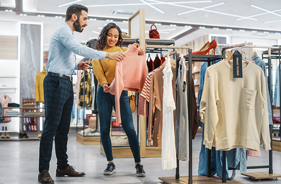 Fashion management training: textiles and clothing salesperson advises a customer. Fashion management training: textiles and clothing salesperson advises a customer.