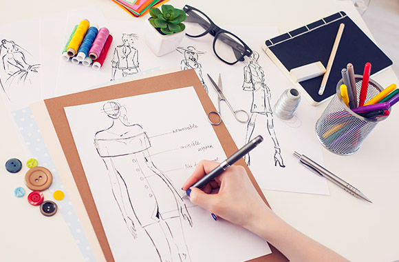 Designer sketches a dress while studying fashion design.