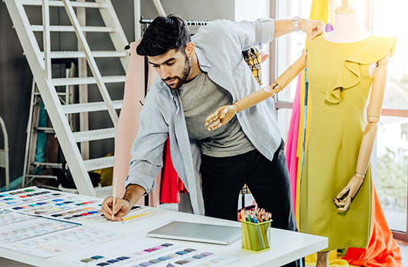 Studying fashion design: a designer working on a yellow dress.
