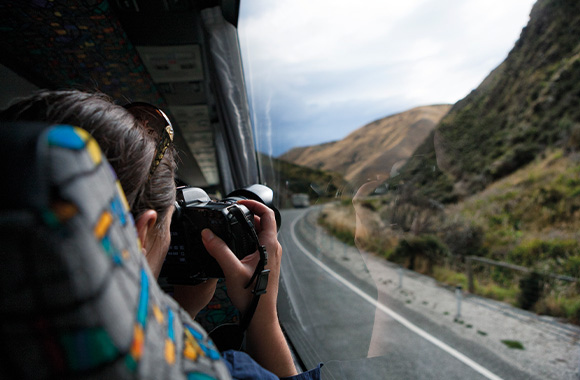 Eco-travel: a woman travelling by coach taking pictures of the passing scenery.