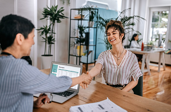 Casually dressed woman introduces herself at a job interview.