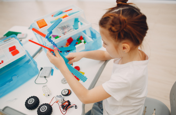 Alt: Gift for 8-year-olds: a little girl assembles a robot with a kit.