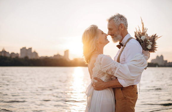 Silver wedding anniversary dress: An elderly couple in formalwear together at the beach.