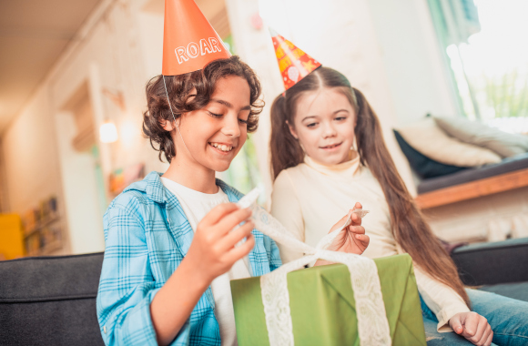 Children's gift from 6 years old. Boy opening his birthday present with his sister.