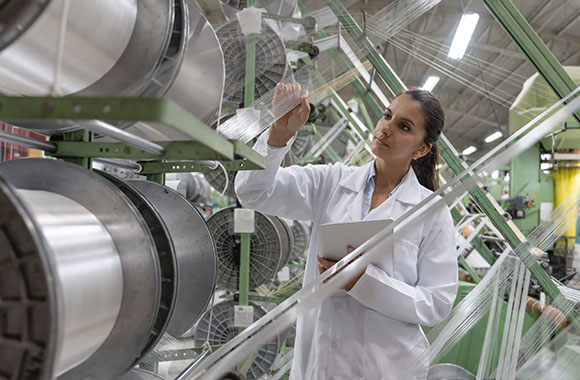 A textile engineer wearing a lab coat and carrying out a quality assessment. A textile engineer wearing a lab coat and carrying out a quality assessment.