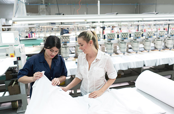 Fashion management: two young women looking at white fabrics in a textile factory. Fashion management: two young women looking at white fabrics in a textile factory.