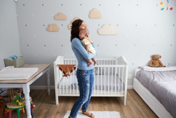 Mutter trägt ihr weinendes Baby im Schlafzimmer umher Mutter trägt ihr weinendes Baby im Schlafzimmer umher