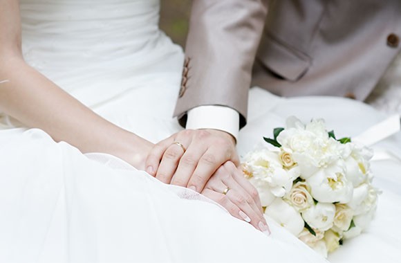 Een bruidspaar houdt elkaars handen vast