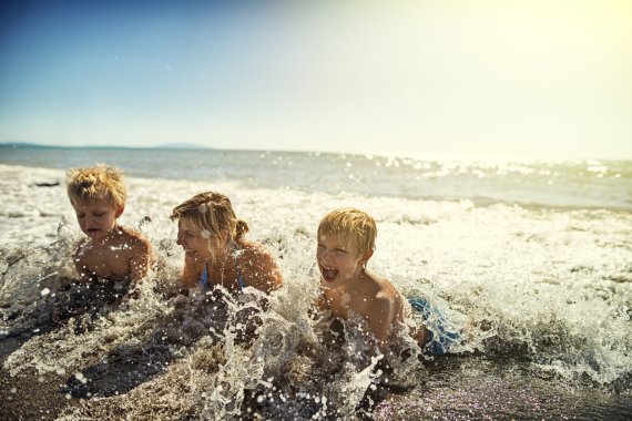 Zwei blonde Jungen planschen mit Mutter im Meer Zwei blonde Jungen planschen mit Mutter im Meer
