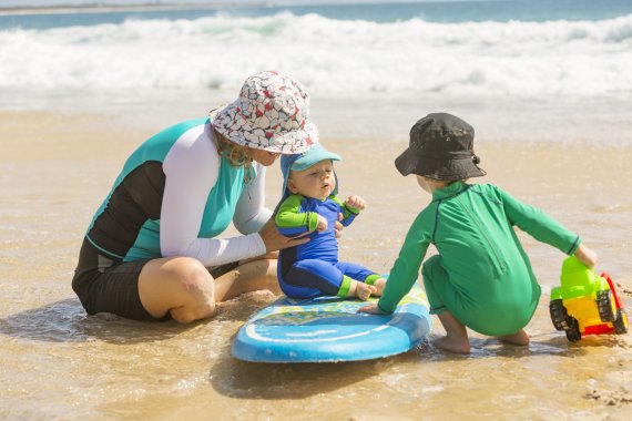 Une mère, un bébé et un enfant avec des chapeaux jouent sur la plage Une mère, un bébé et un enfant avec des chapeaux jouent sur la plage