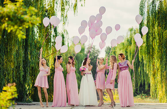 Bruid met bruidsmeisjes in roze kleding en ballonnen