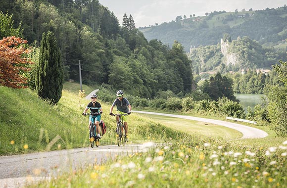 Zwei Radfahrer fahren auf dem Ennsradweg mit Blick auf die Burg Losenstein.