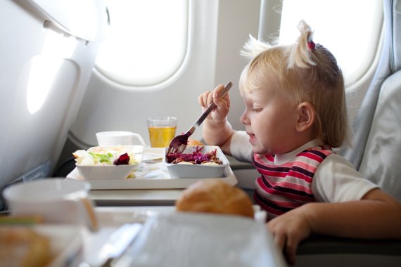 Kleines Mädchen beim Essen im Flugzeug Kleines Mädchen beim Essen im Flugzeug