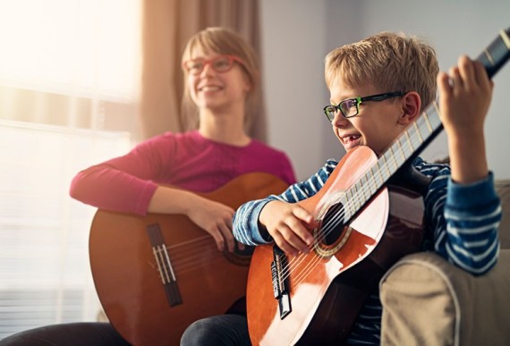 Deux enfants aprennent à faire de la guitare