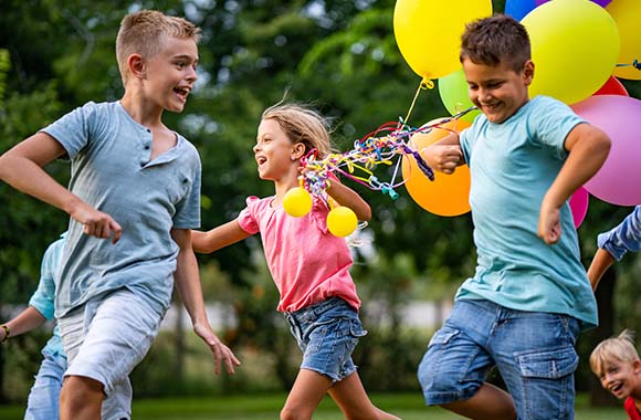 Grappige kinderfeestjes voor buiten, kinderen met ballonnen in de tuin
