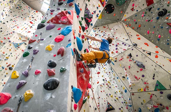 Kletterhalle – Mann klettert im Vorstieg die Kletterwand hoch
