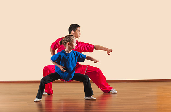 Dziewczynka z instruktorem podczas lekcji kung fu - © iStock.com/Tuned_In Dziewczynka z instruktorem podczas lekcji kung fu